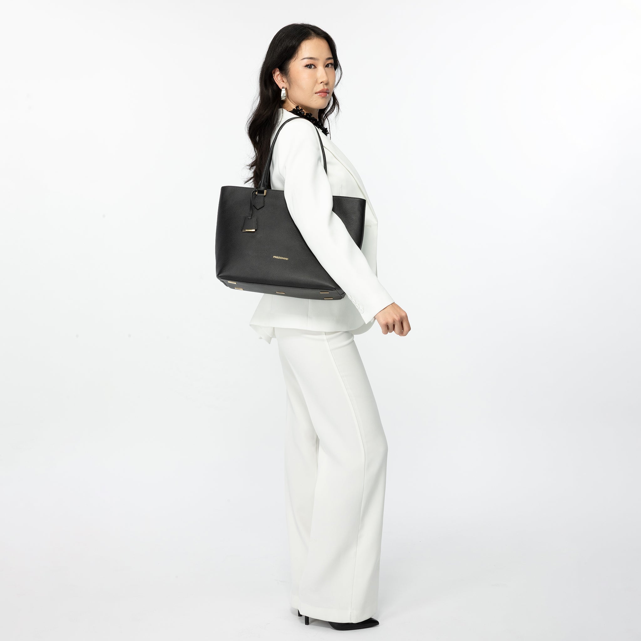 Woman holding a black luxury bag against a white background