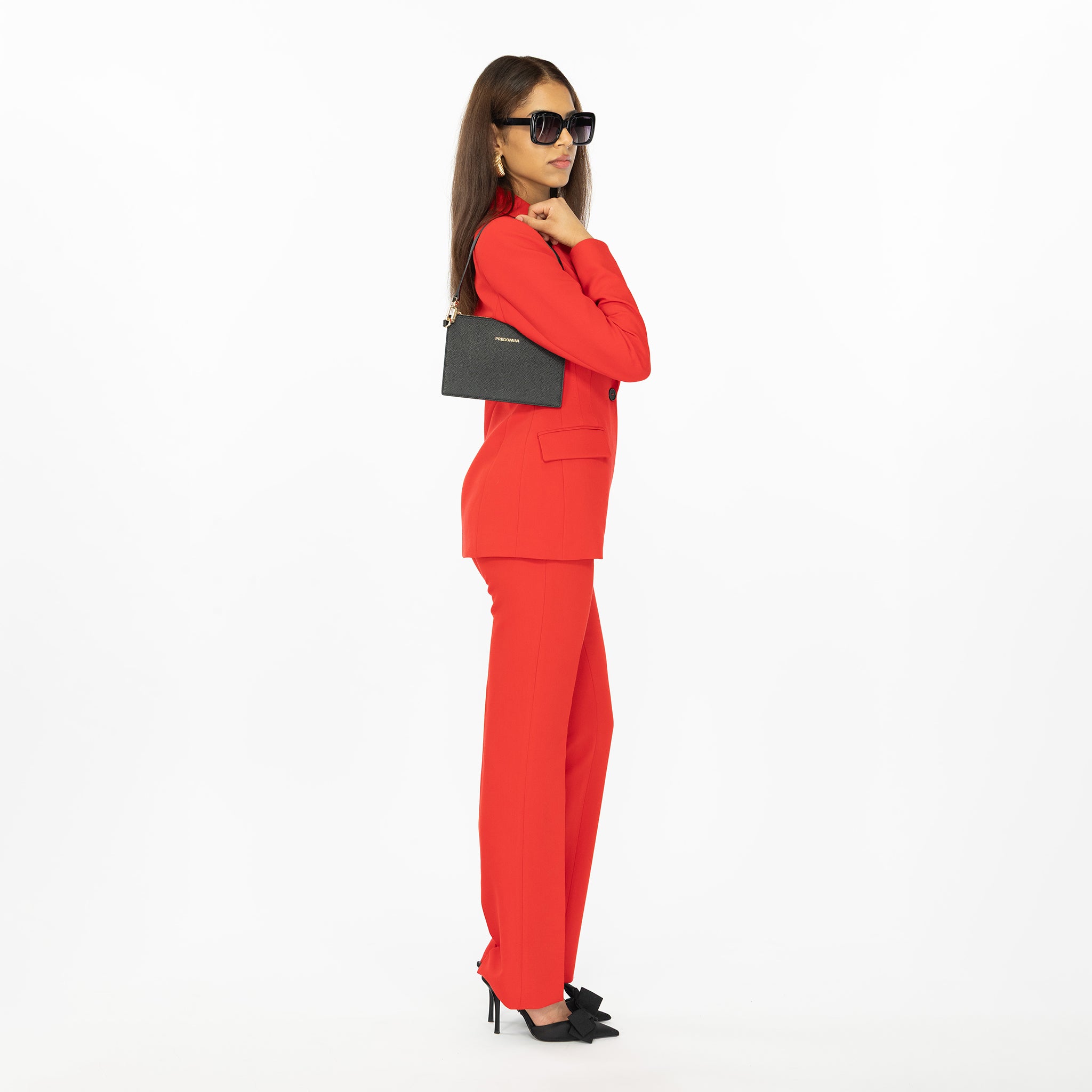 Woman in a red suit holding a black handbag from PREDOMINI on a white background